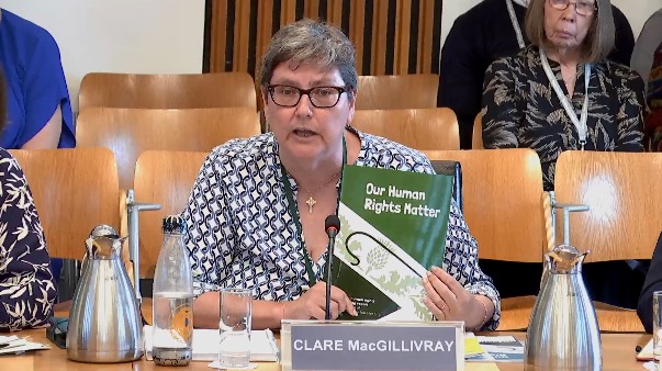 Clare holds up the second report on Human Rights Monitoring in Double Dykes